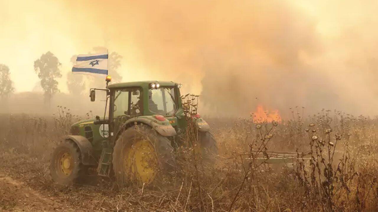 un tractor si steagul Israelului pe un camp care arde